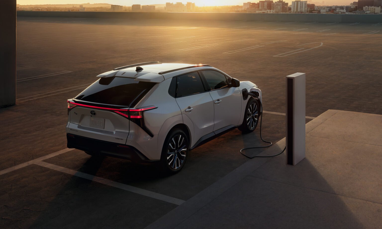 White 2027 Toyota bZ Limited charging on a rooftop parking deck
