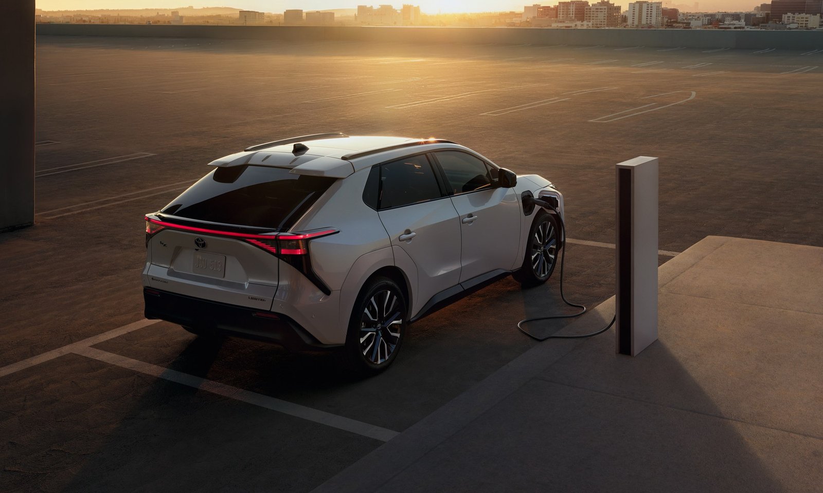 2027 Toyota bZ electric SUV plugged into a charger at sunset