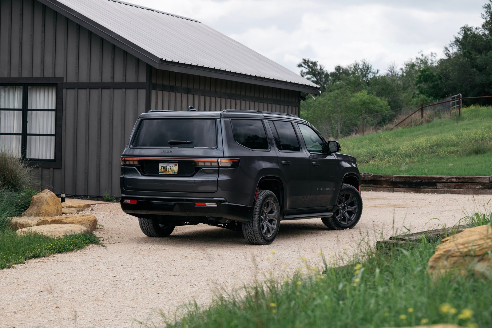 2026 Jeep Grand Wagoneer, rear three-quarter view, parked beside a barn