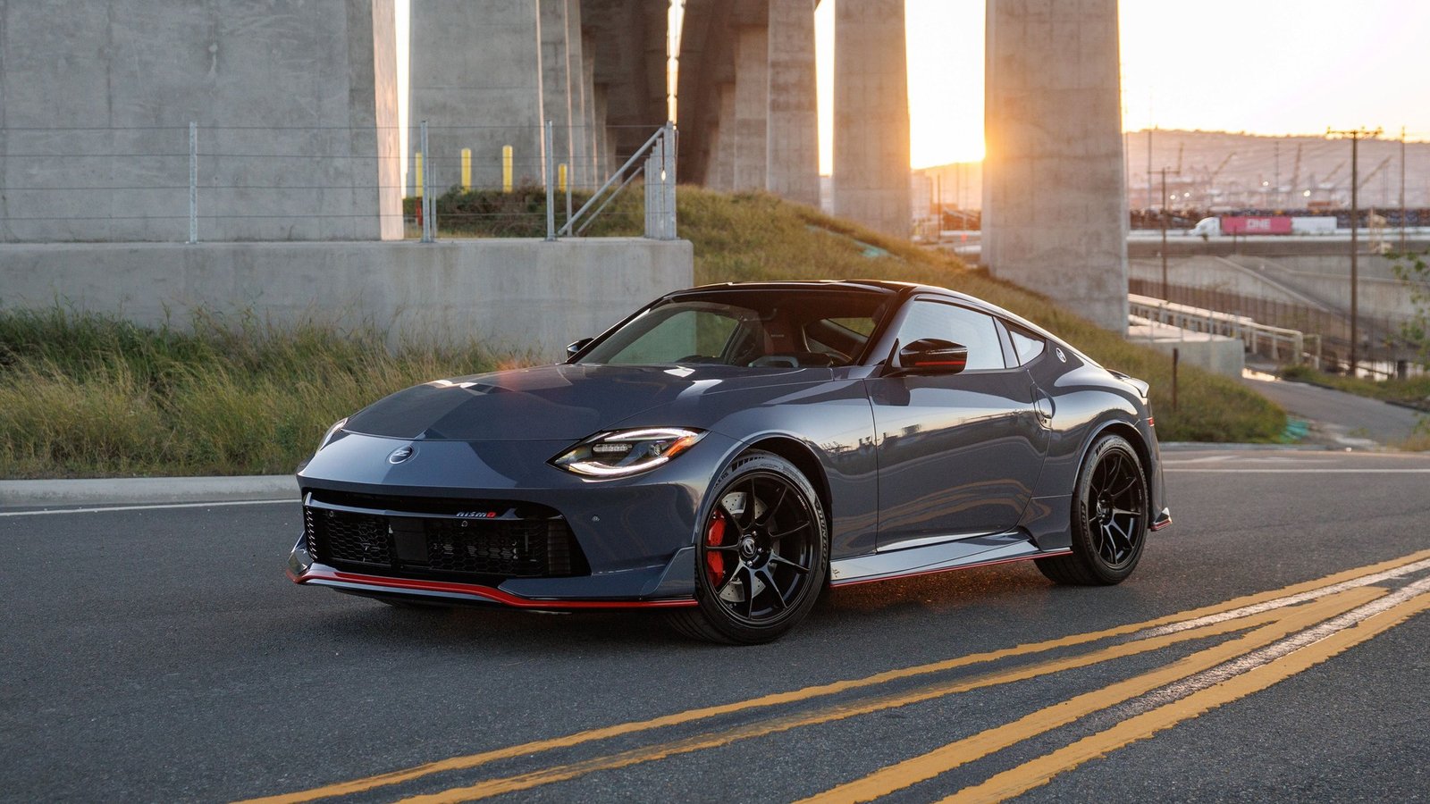 2027 Nissan Z NISMO with manual transmission cornering under a highway bridge at sunset