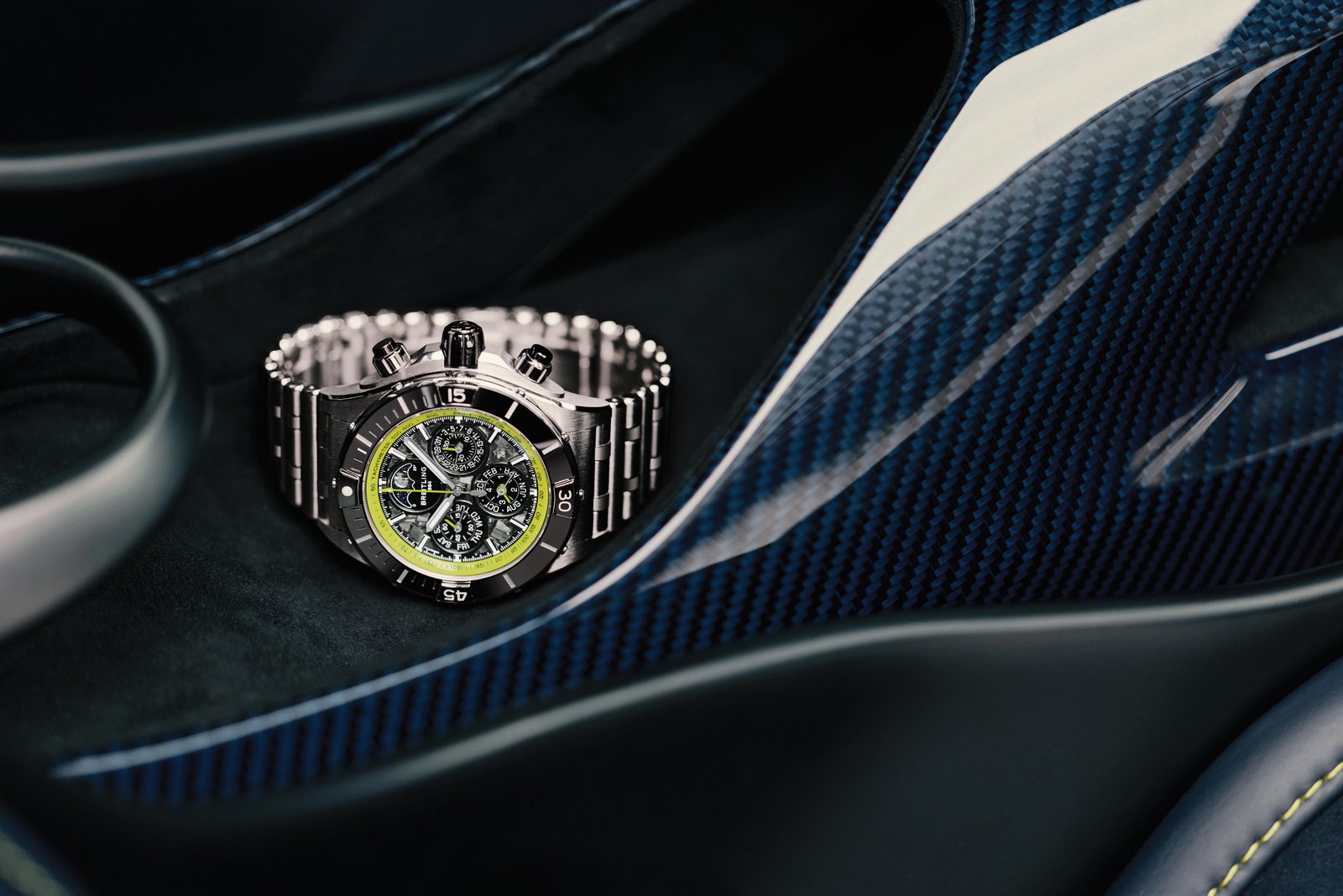 Breitling Super Chronomat B19 44 on a Rouleaux bracelet against Aston Martin carbon trim