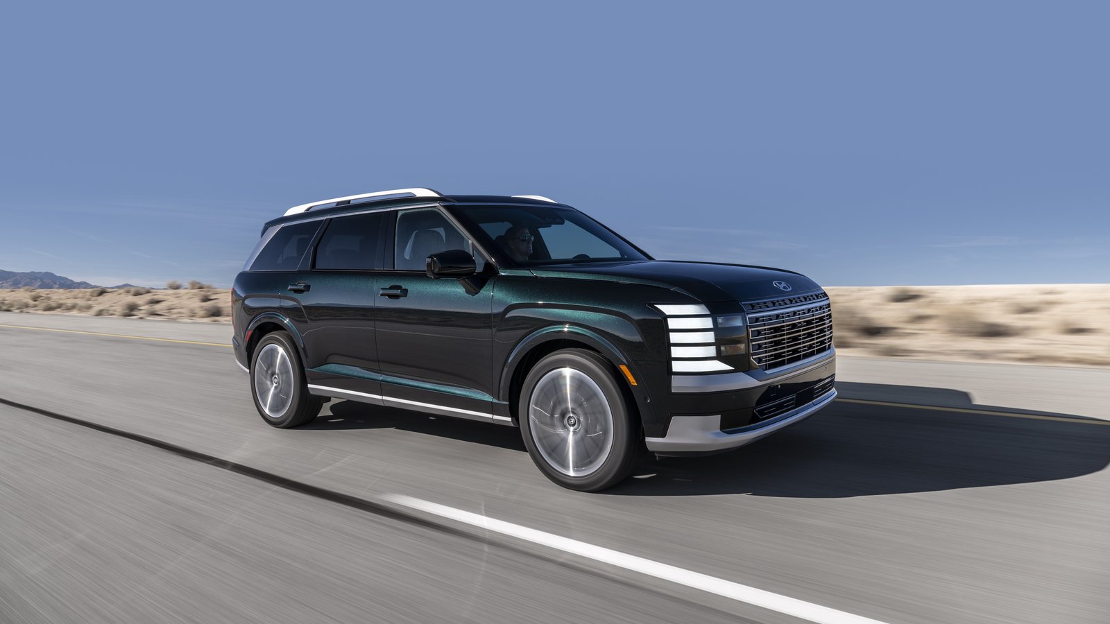 2026 Hyundai Palisade Hybrid driving on a desert road, front three-quarter