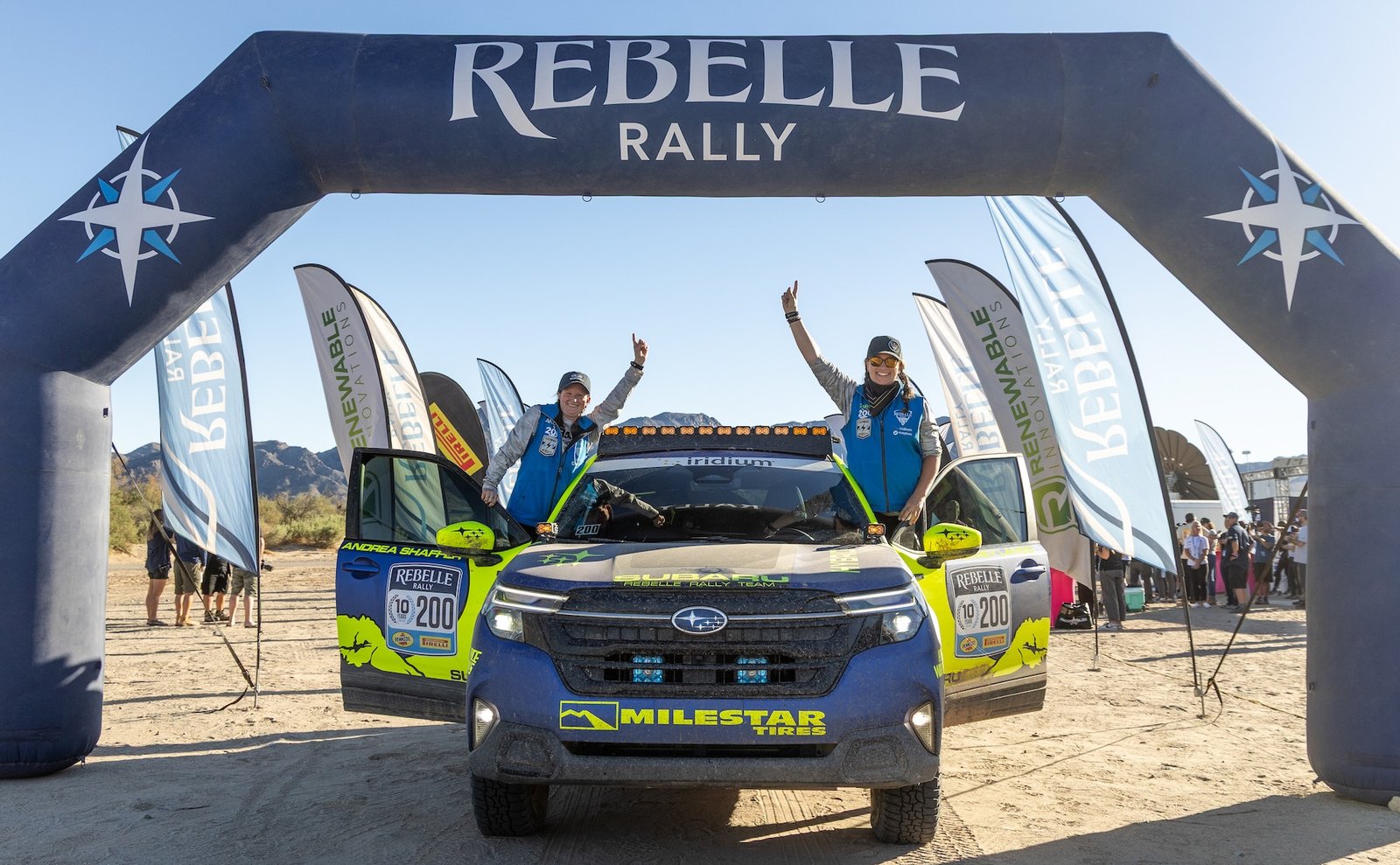 Carey Lando and Andrea Shaffer celebrating on their Subaru under the Rebelle finish arch