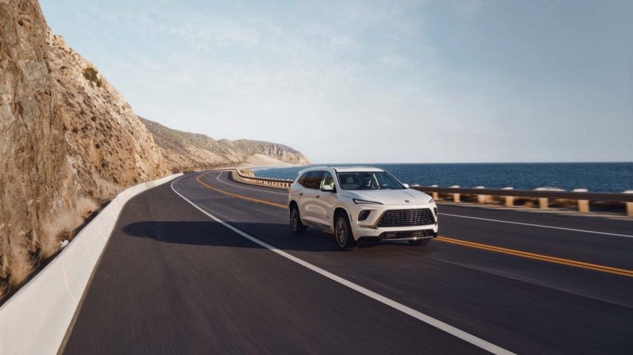 White Buick Enclave driving on a coastal highway beside cliffs