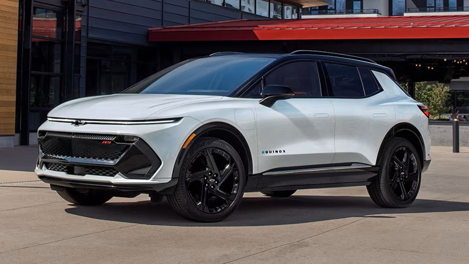 White 2027 Chevrolet Equinox EV RS parked outside a building, front three-quarter view