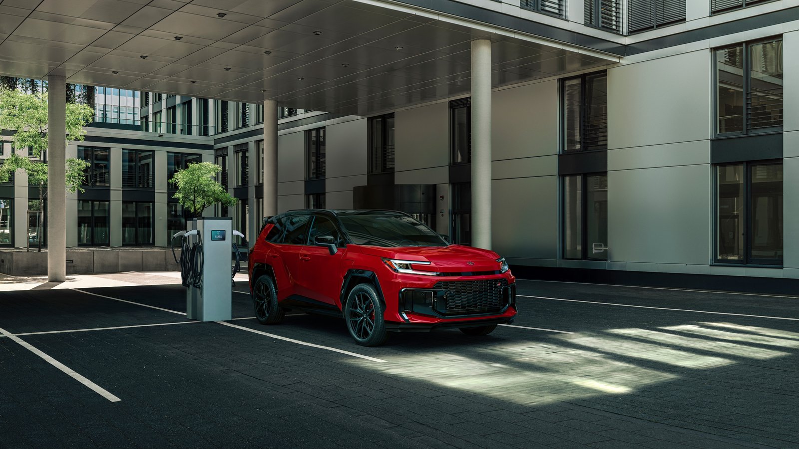 Red Toyota RAV4 Plug-in Hybrid parked next to a charging station