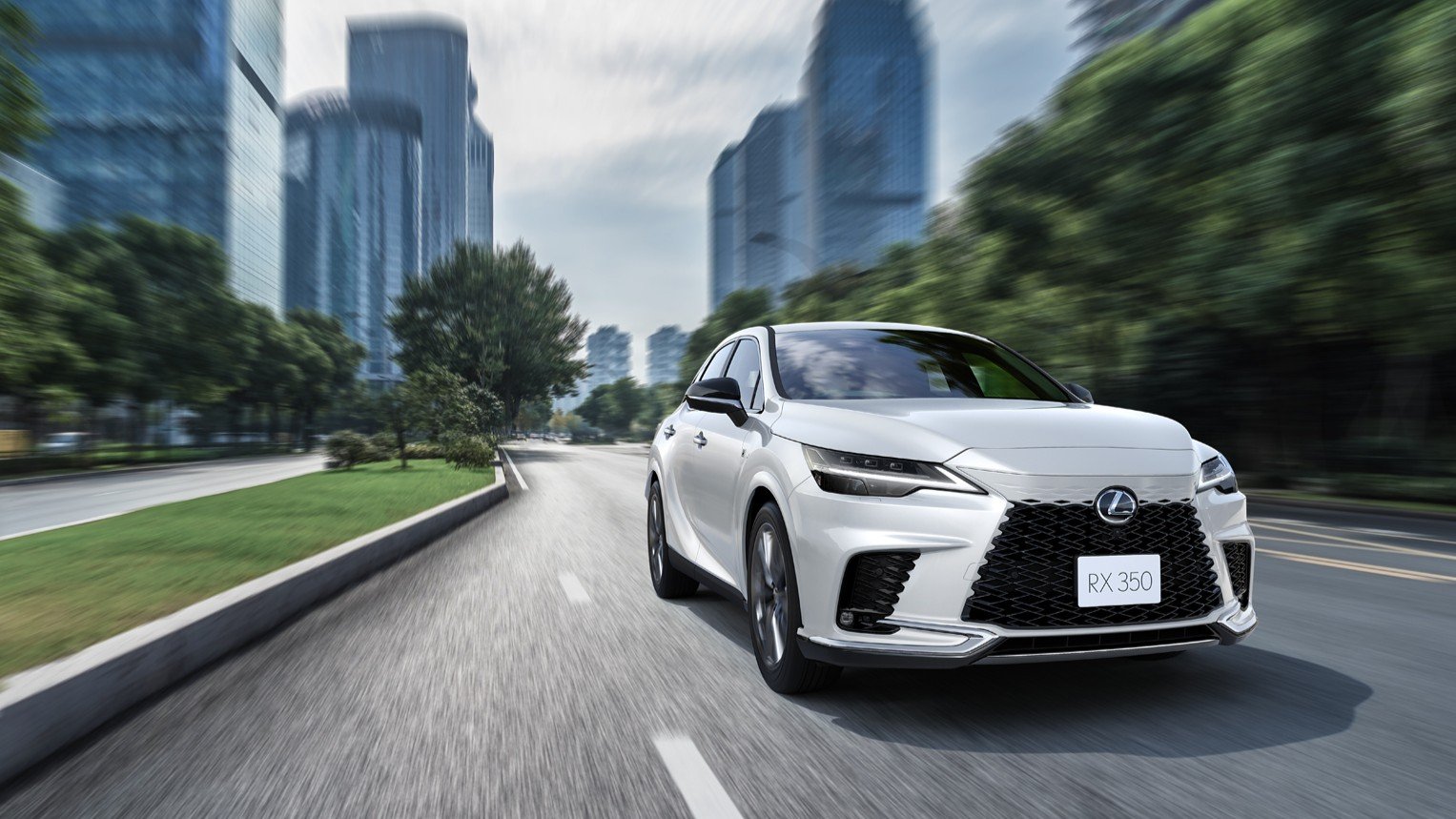 White Lexus RX 350 driving through a city with high-rise buildings