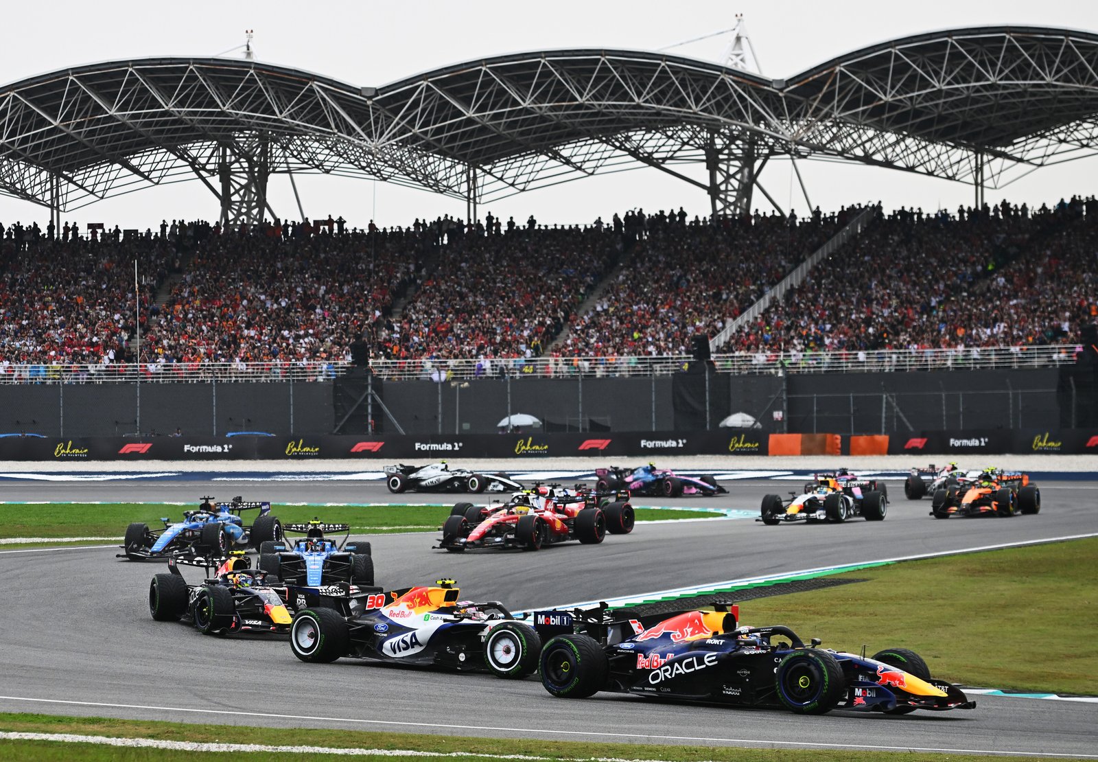 A Red Bull leads a Racing Bulls car and the pack at Sepang
