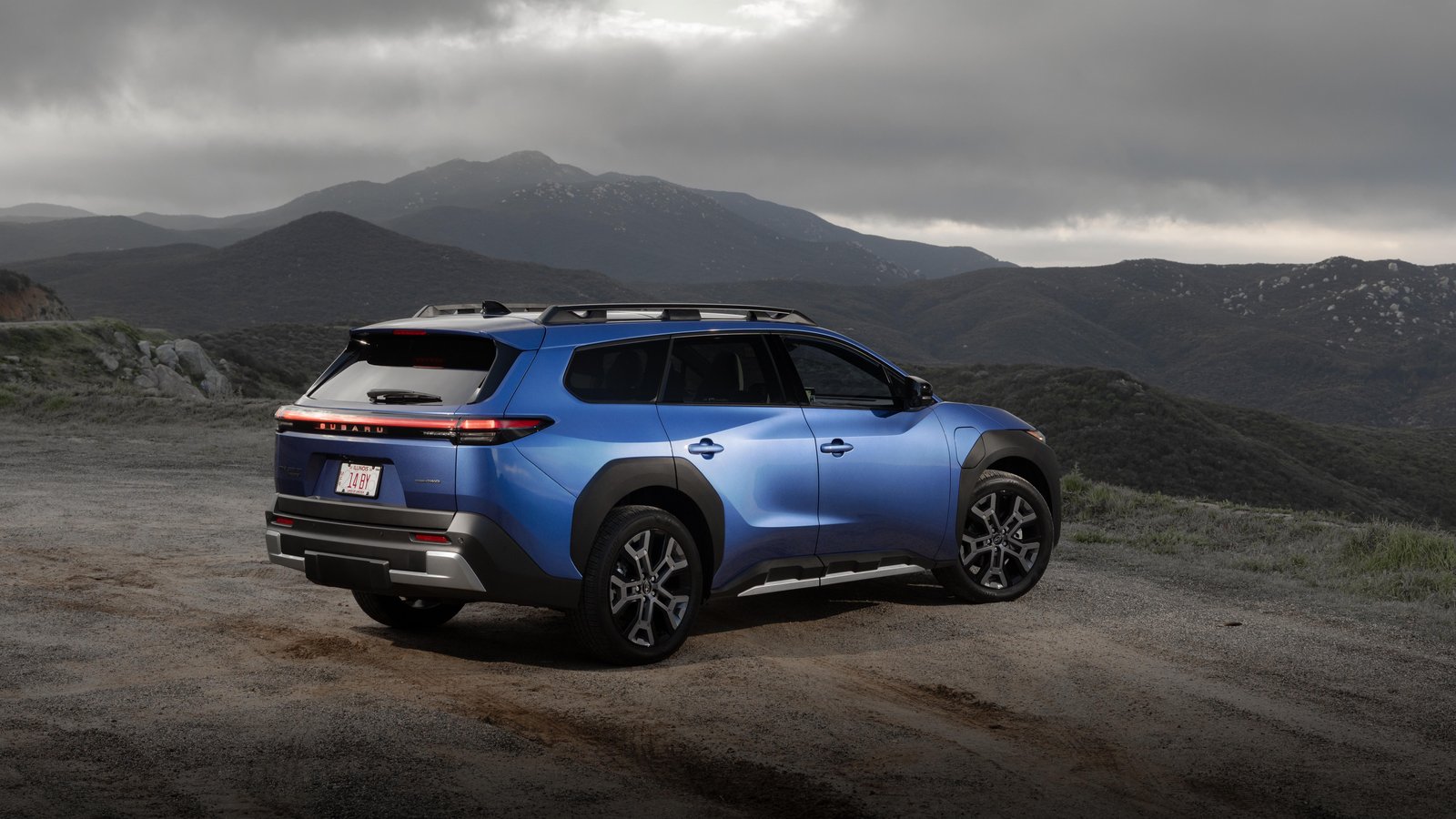 Rear three-quarter view of a blue Subaru Trailseeker on a dirt overlook