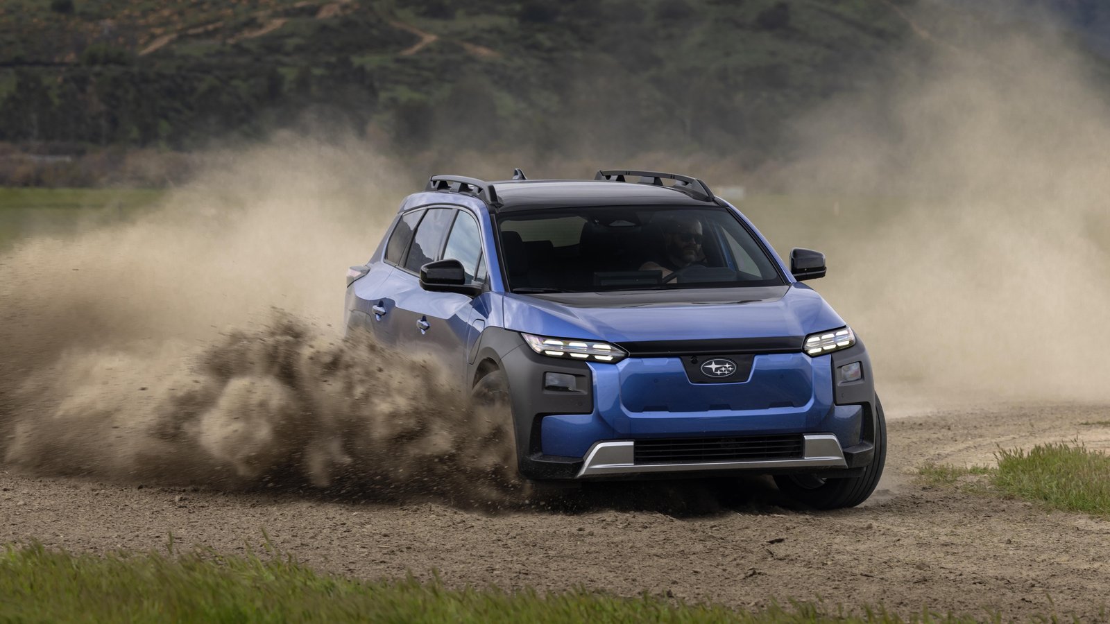 Blue Subaru Trailseeker sliding on a gravel road with dust behind