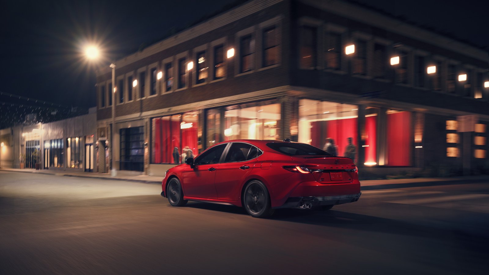 2027 Toyota Camry Nightshade rear three-quarter view on a city street at night