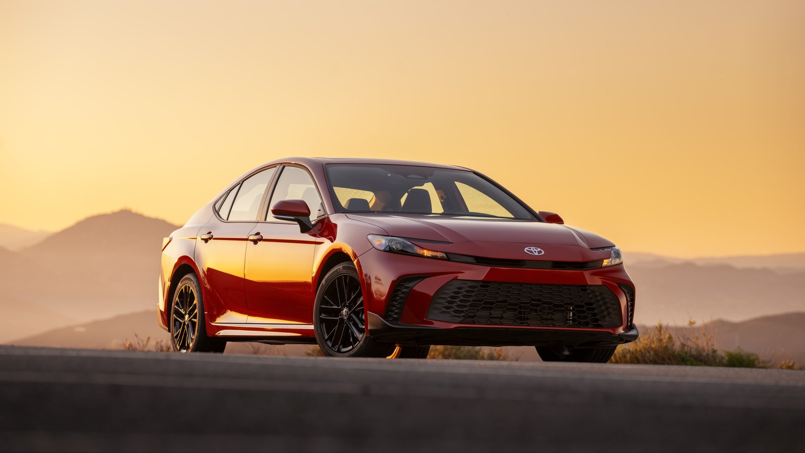 Red 2027 Toyota Camry SE AWD front three-quarter view at sunset