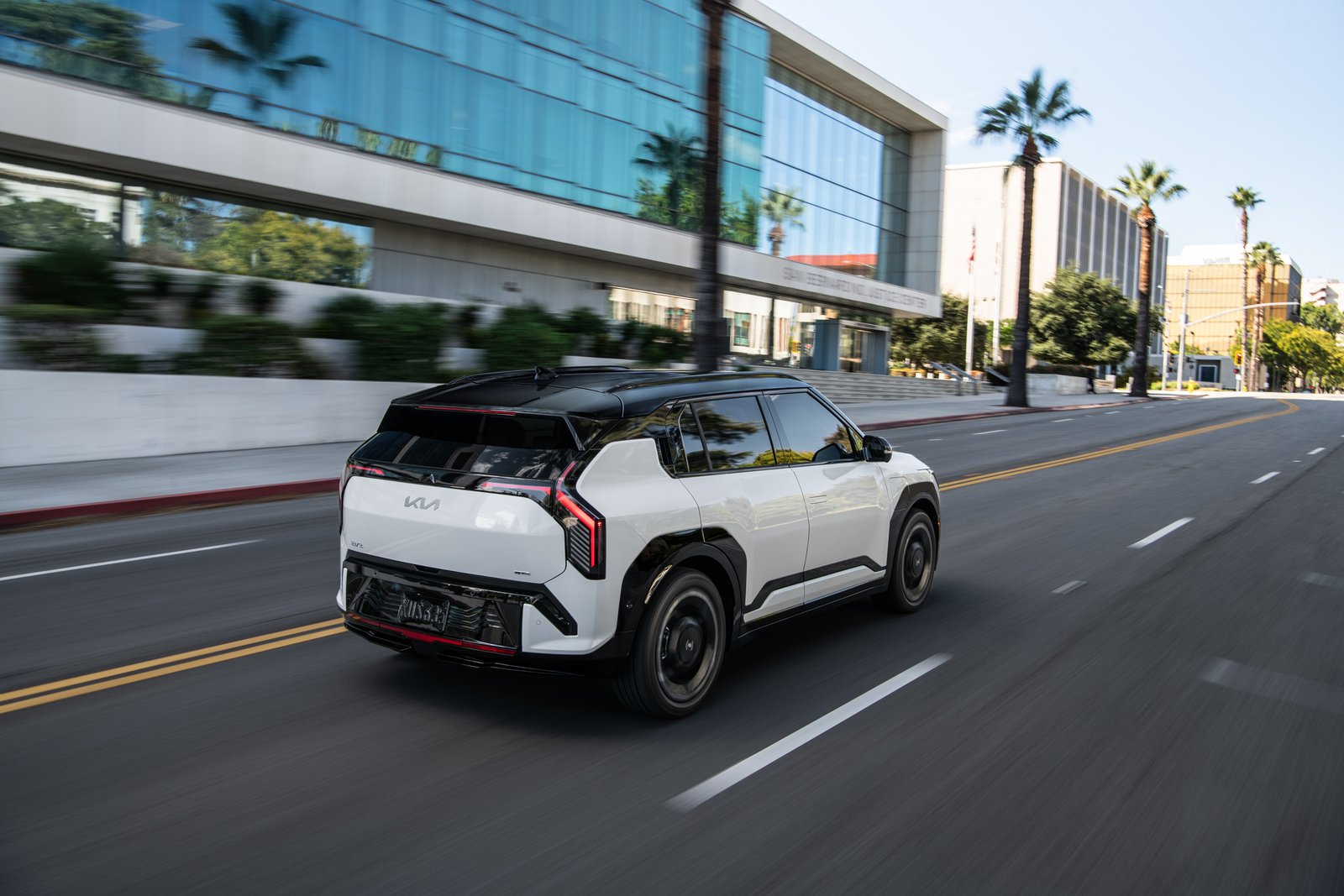 2027 Kia EV3 driving down a palm-lined city street