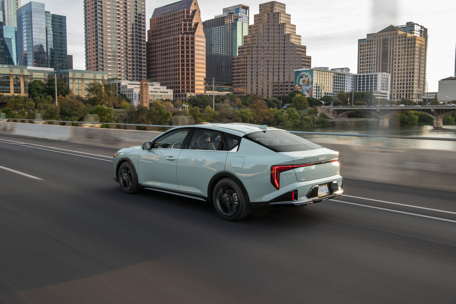 2027 Kia K4 sedan rear three-quarter view driving on a highway