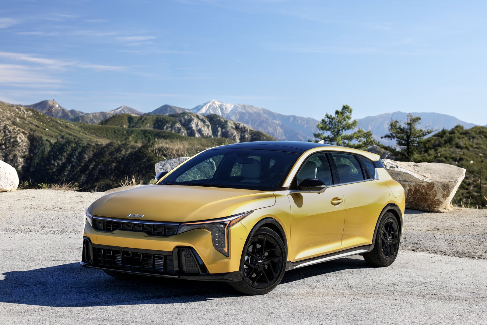 Yellow 2027 Kia K4 Hatchback front three-quarter view on a mountain road