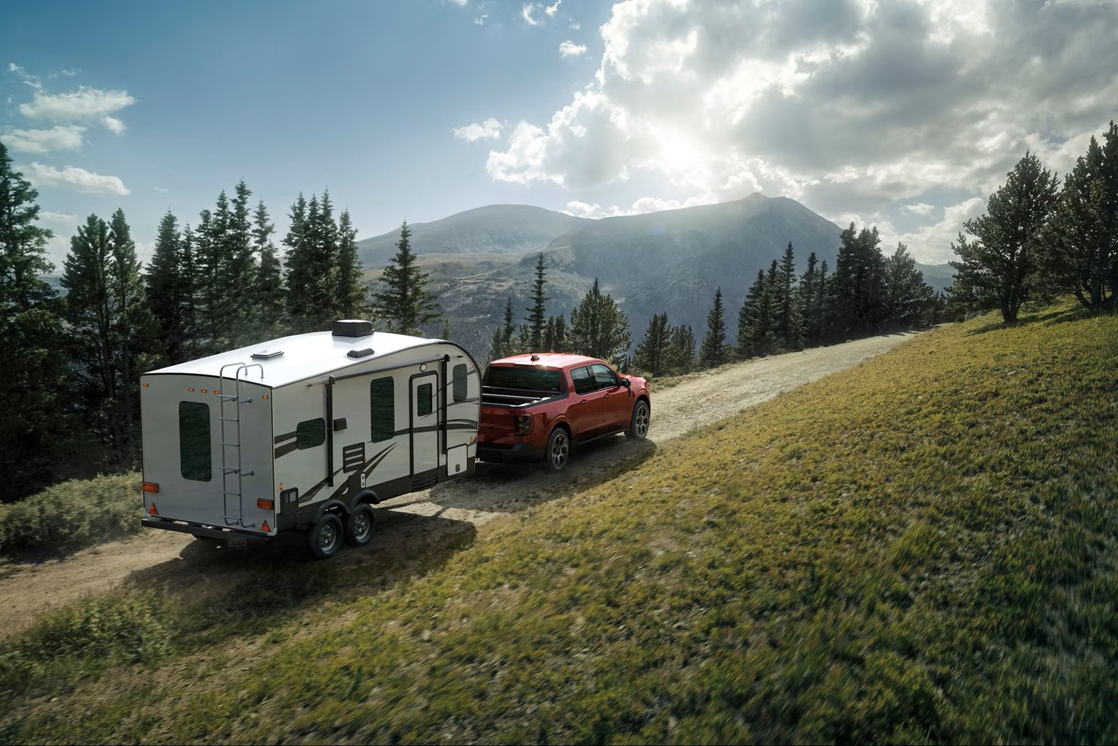 Red Ford Maverick pickup towing a travel trailer on a mountain road