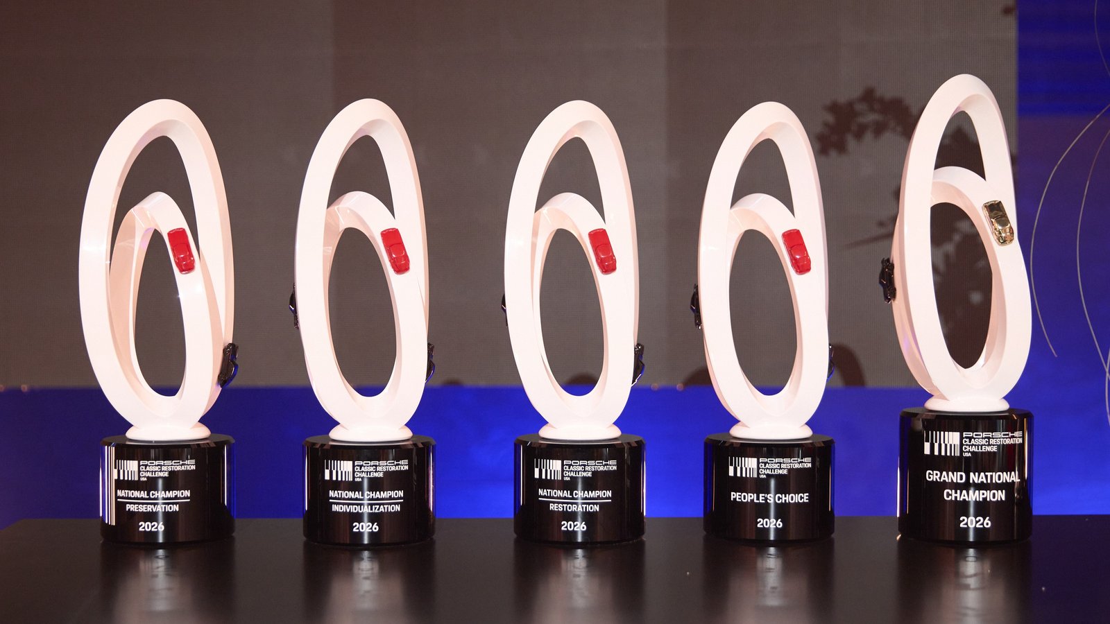 Five 2026 Porsche Classic Restoration Challenge trophies lined up on stage