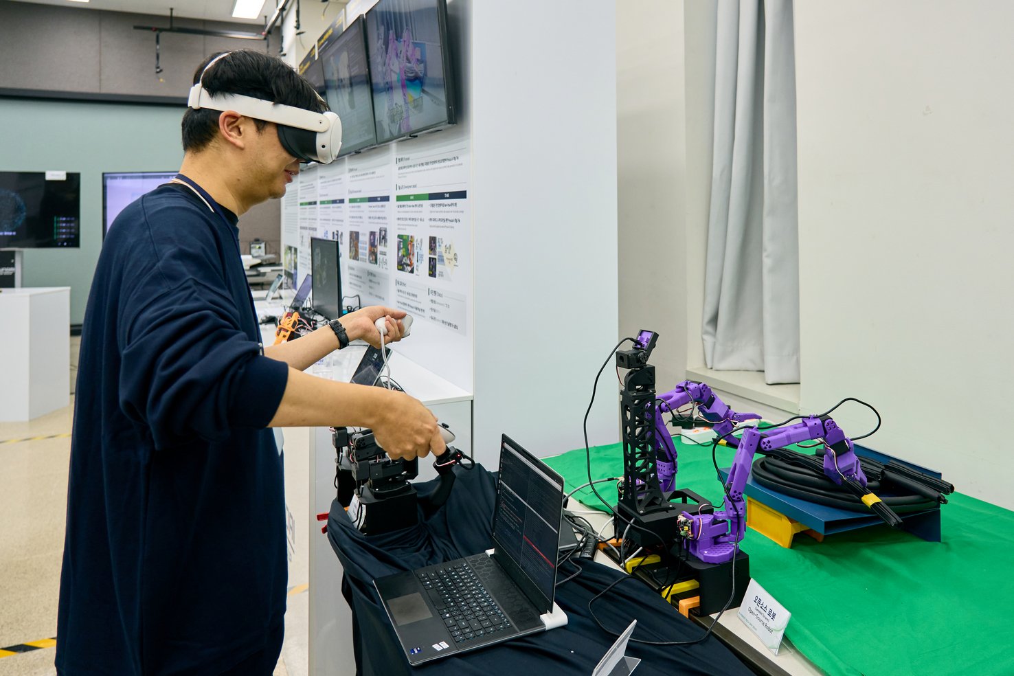Engineer in a VR headset teleoperates a small open-source robot arm
