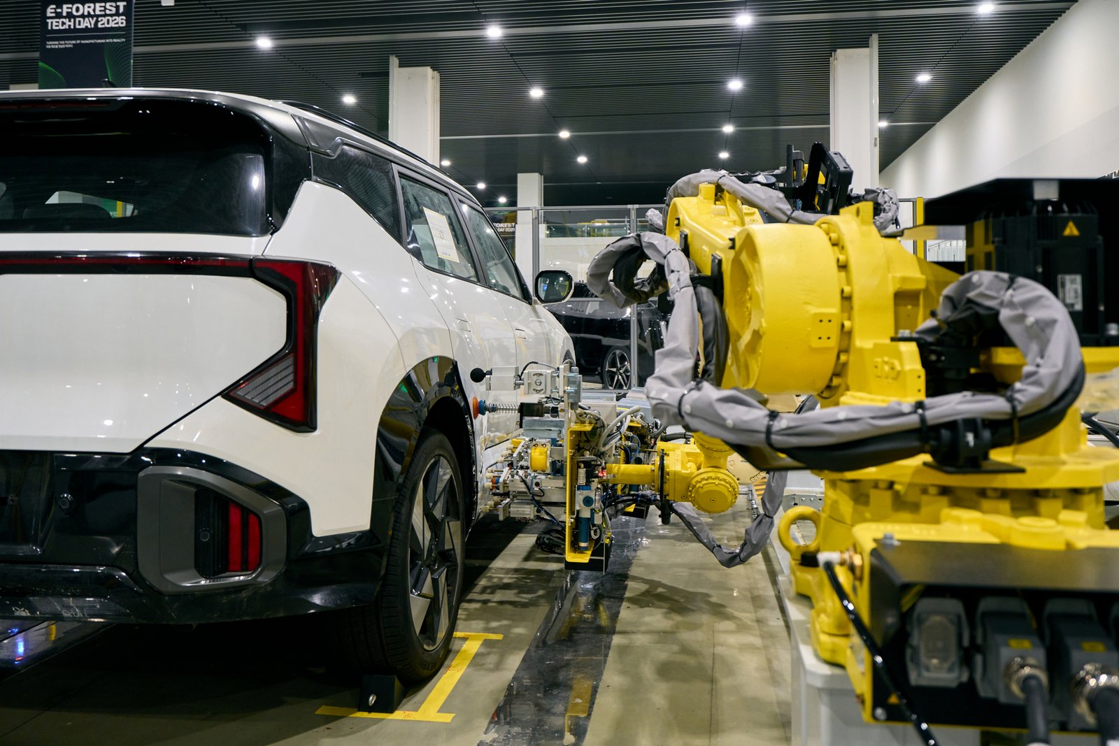 Yellow robot arm works on a white Kia EV at E-FOREST TECH DAY 2026