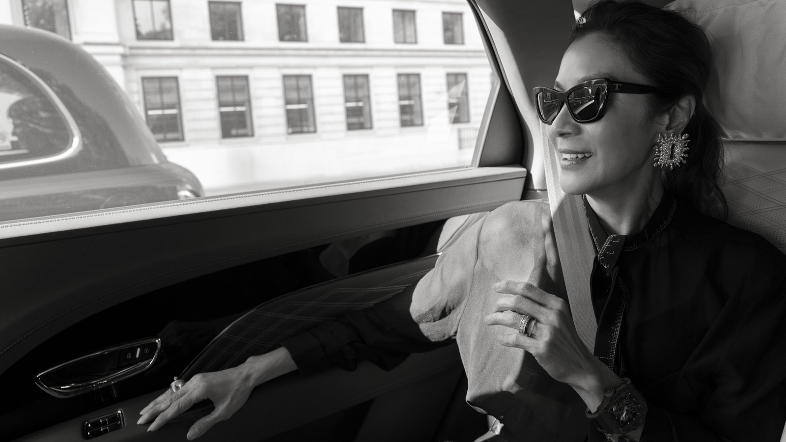 Michelle Yeoh smiling in the rear seat of a Bentley