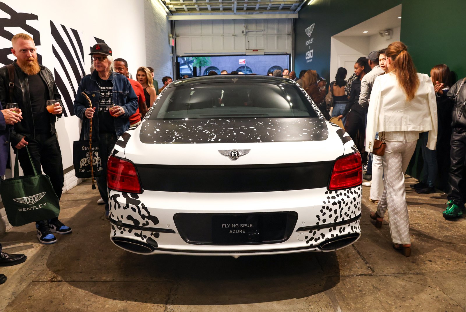 Rear view of the Death Spray Custom Flying Spur art car among gallery guests