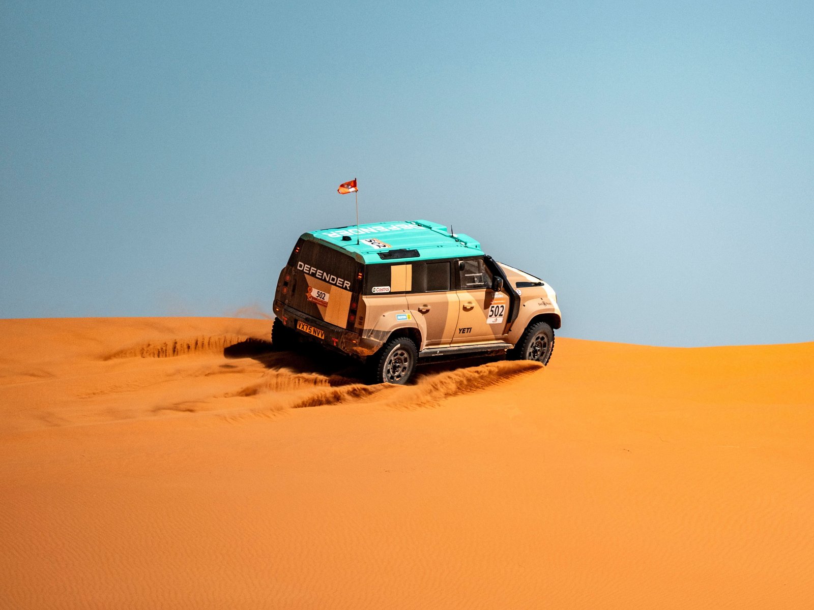 Defender D7X-R number 502 climbing an orange sand dune