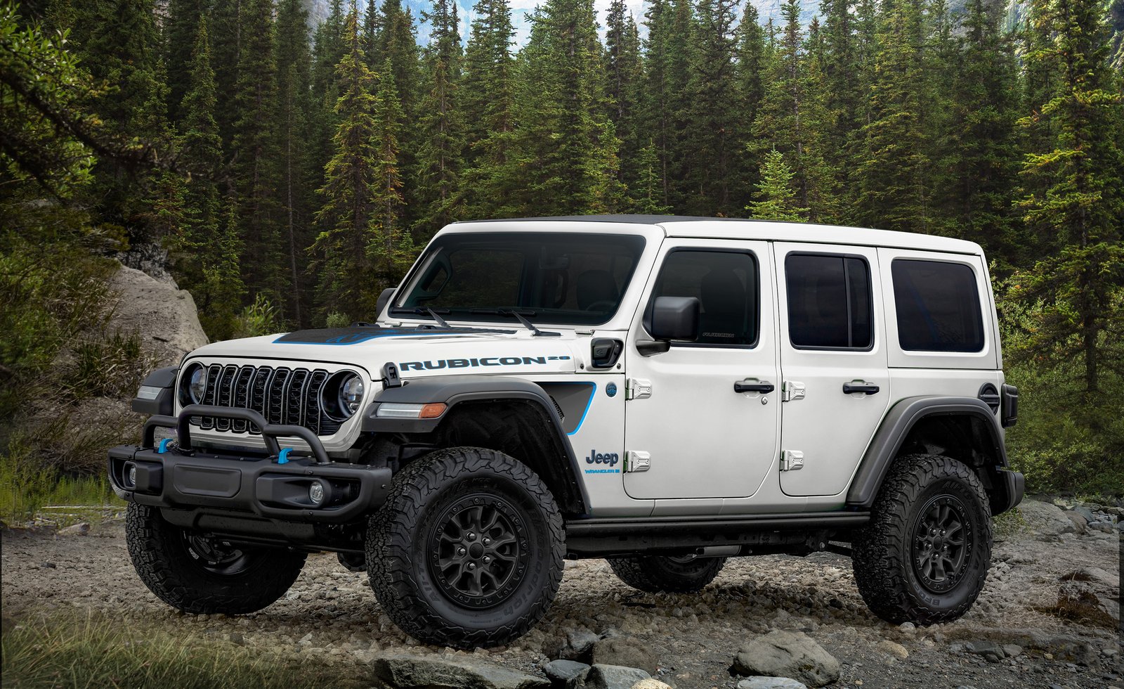 White Jeep Wrangler Rubicon 4xe parked on rocks in a pine forest