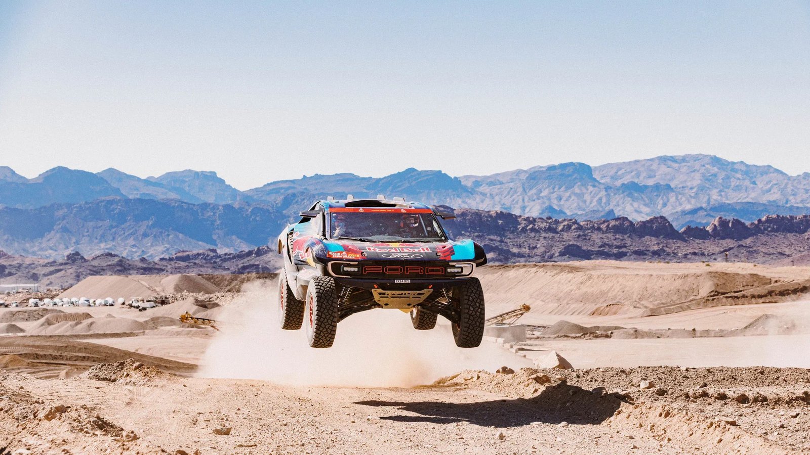 Ford Raptor T1+ Dakar race truck airborne over a desert jump