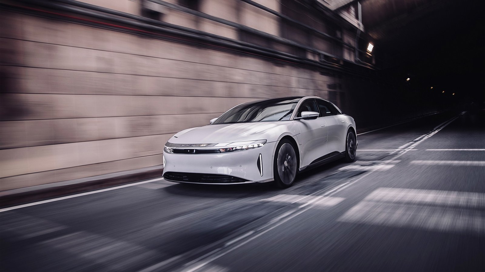 White Lucid Air electric sedan driving through a tunnel, front three-quarter view