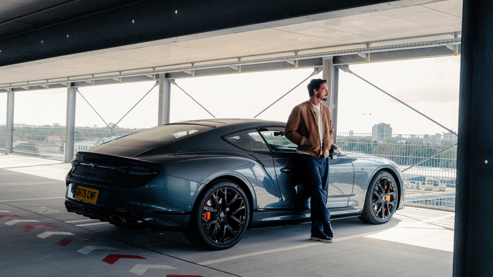 Mats Hummels leaning on a Bentley Continental GT Speed coupe, rear view