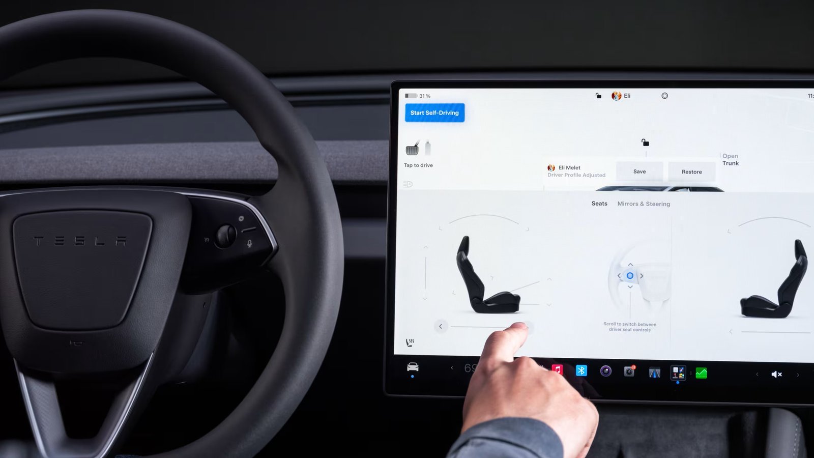 Driver adjusting seat settings on Tesla Model 3 center touchscreen