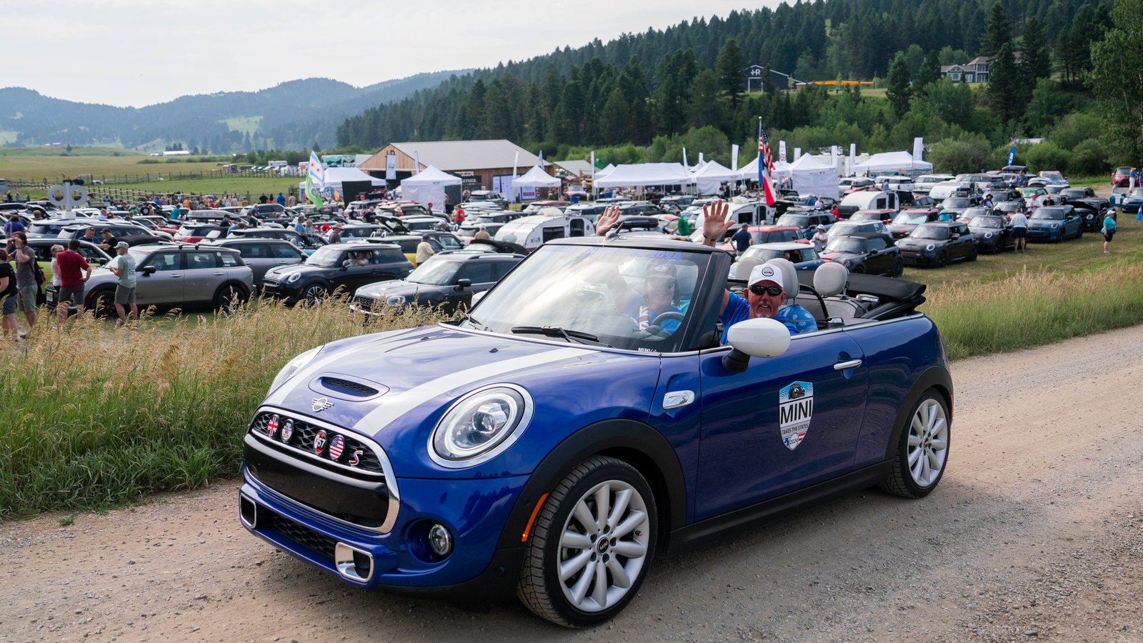 Owners waving from a blue MINI Cooper S Convertible at a 2024 rally stop