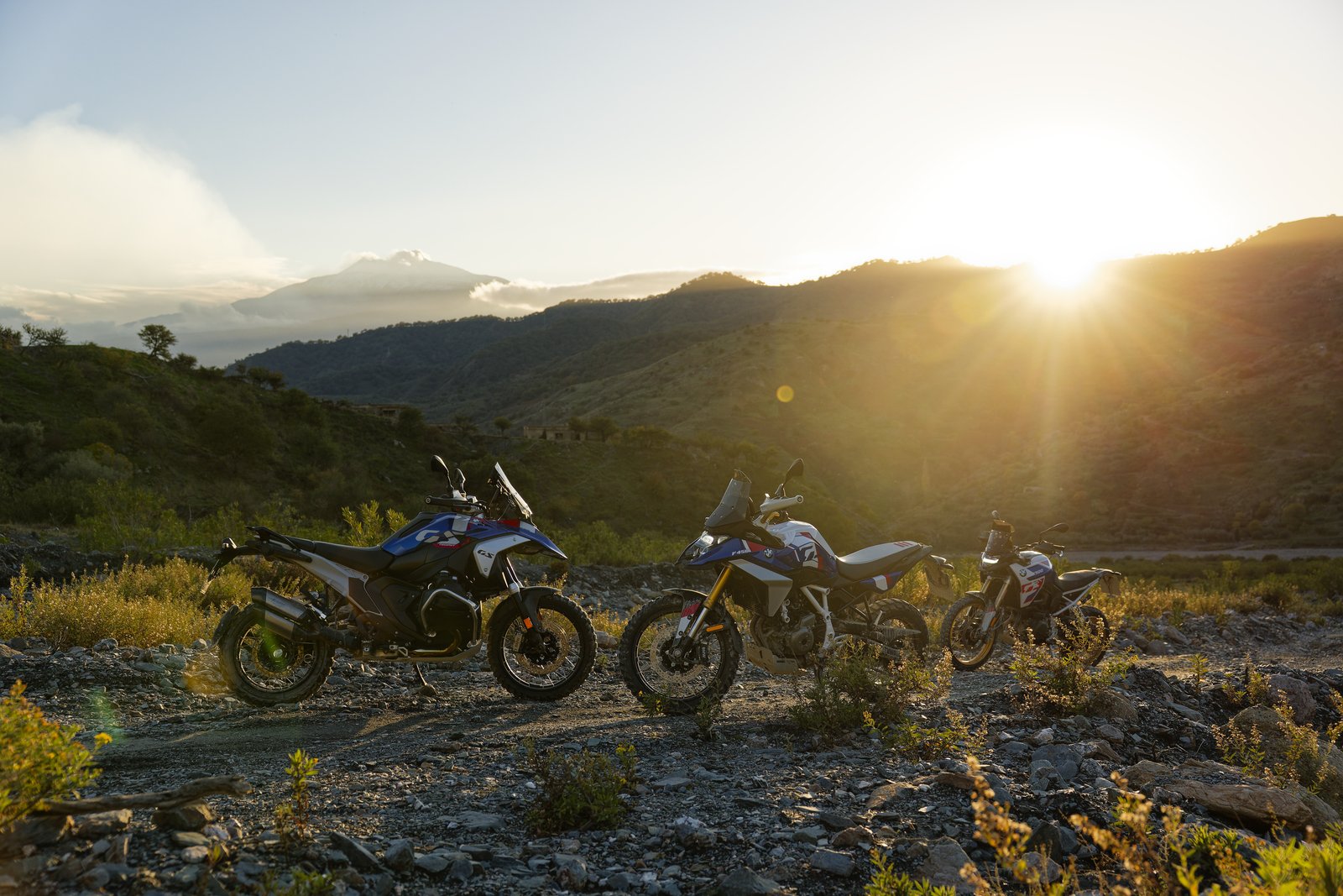 BMW R 1300 GS, F 450 GS, and F 900 GS lined up at sunset