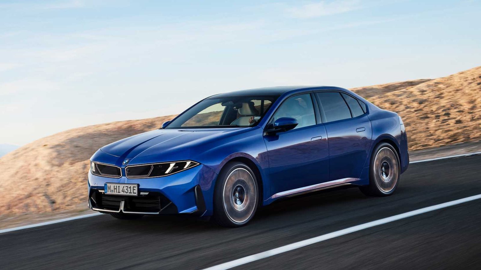 Blue 2027 BMW i3 50 xDrive electric sedan on a coastal road