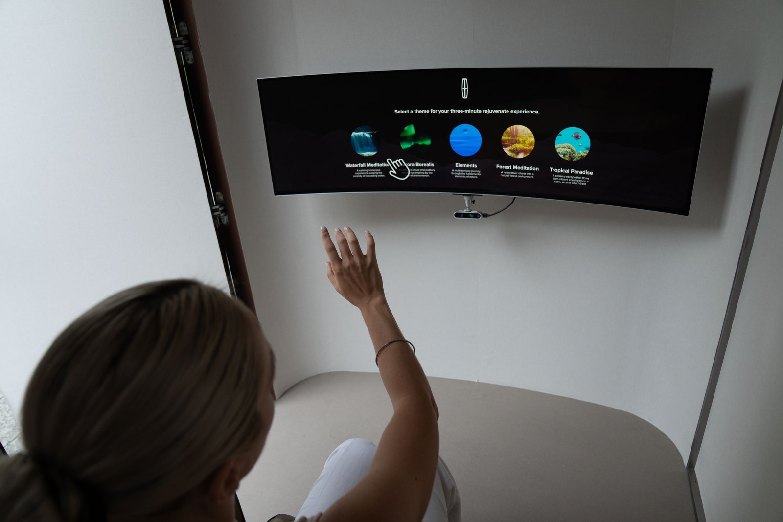 Guest waves a hand to choose a theme on the pod’s curved screen