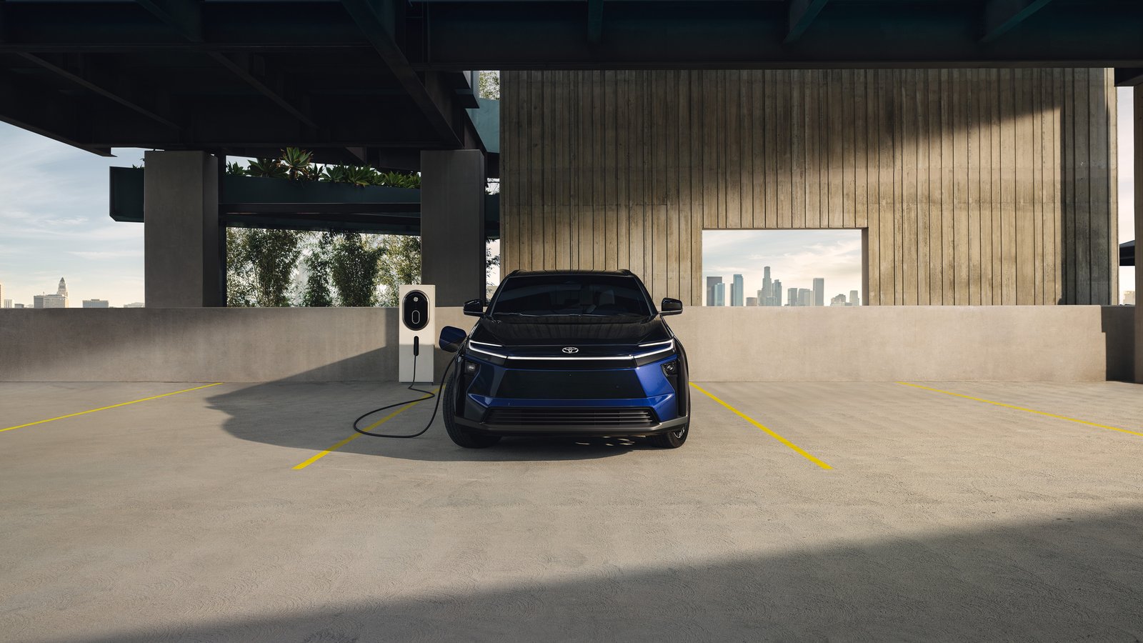 Blue Toyota bZ charging in a parking structure, front view