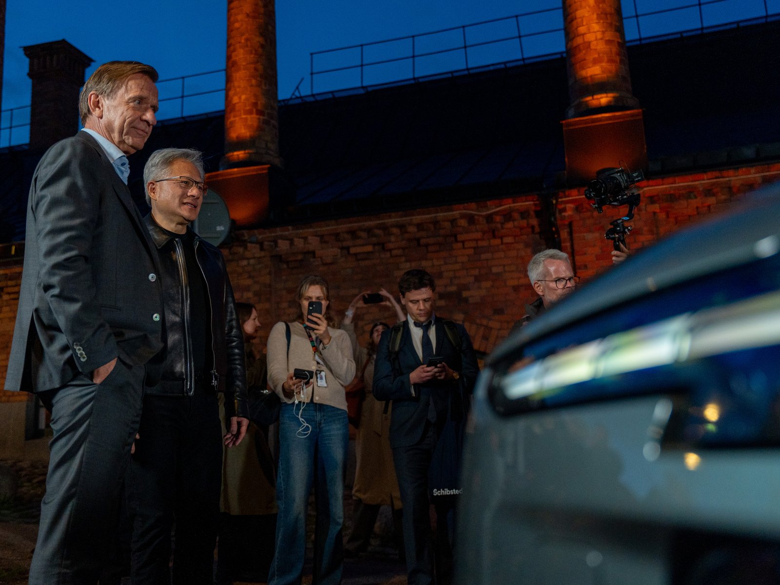 Volvo and NVIDIA chiefs watched by journalists outside a brick building
