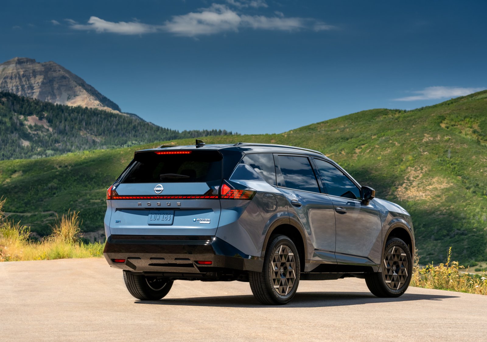 2027 Nissan Rogue Hybrid SR rear three-quarter view with e-POWER badge, mountains behind