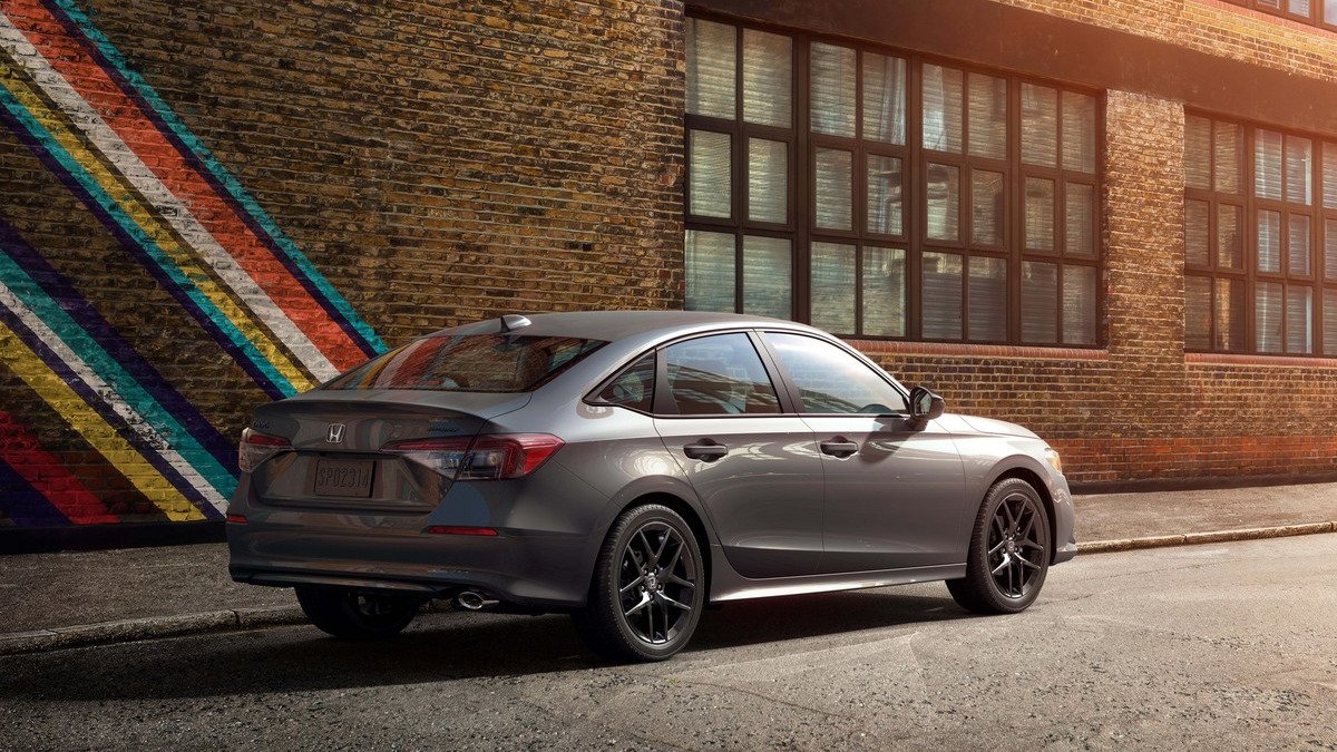 Gray 2027 Honda Civic sedan parked by a brick wall, rear three-quarter view