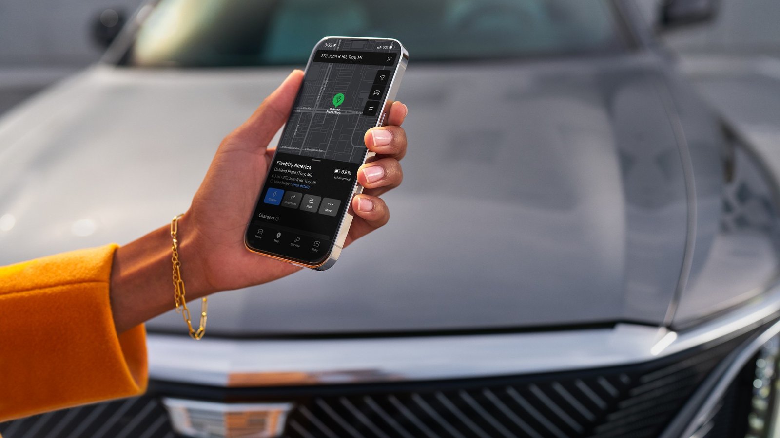 Hand holding a phone with the Cadillac app in front of a Cadillac hood