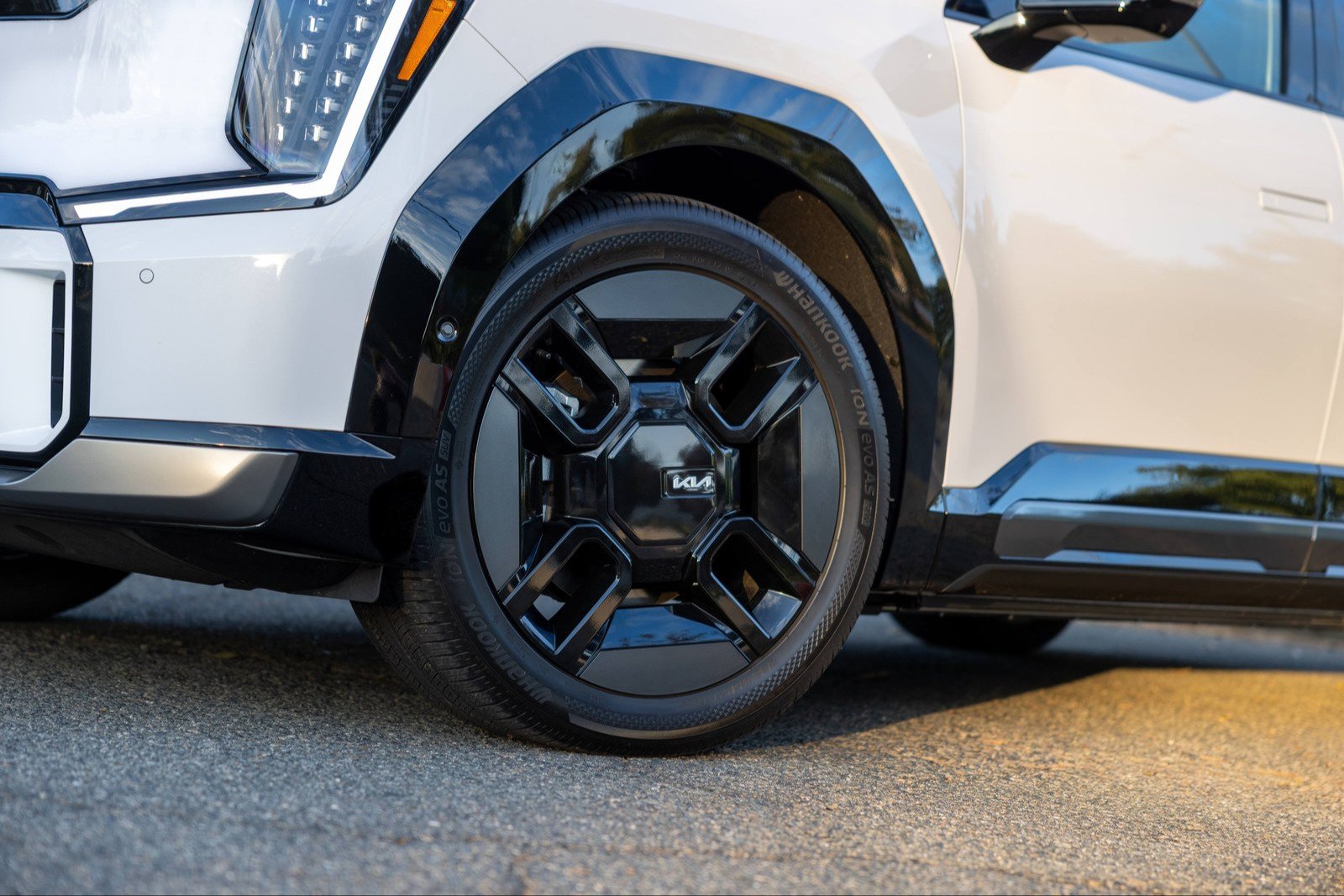 Black-finish wheel and gloss black fender trim on a white Kia EV9