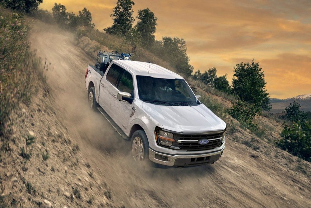 White 2026 Ford F-150 climbing a dirt trail at dusk