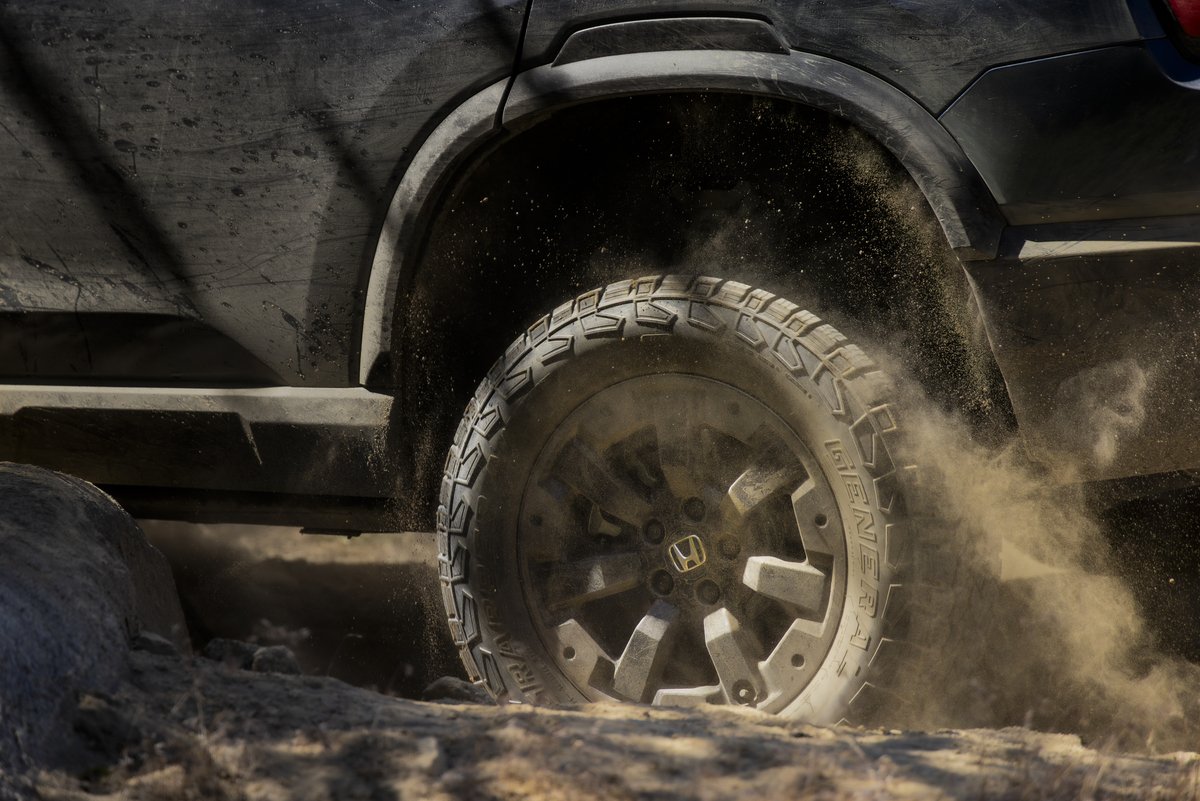 Honda Passport TrailSport wheel and all-terrain tire kicking up dust