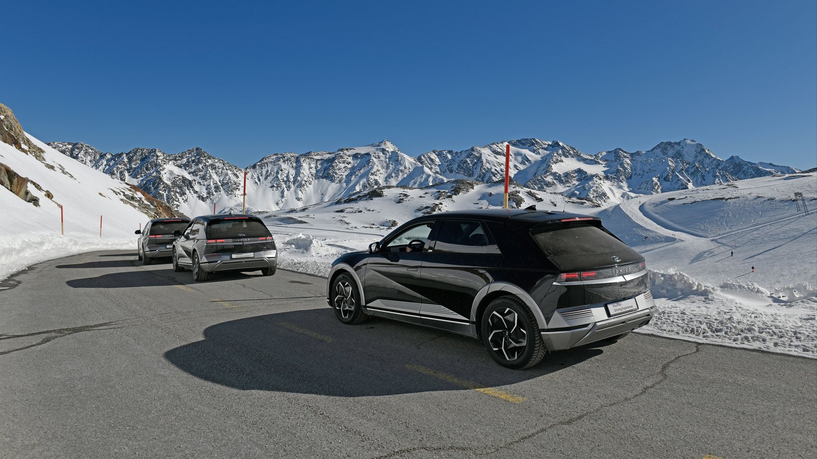 Three Hyundai Ioniq 5 crossovers on a cleared mountain road between snowbanks
