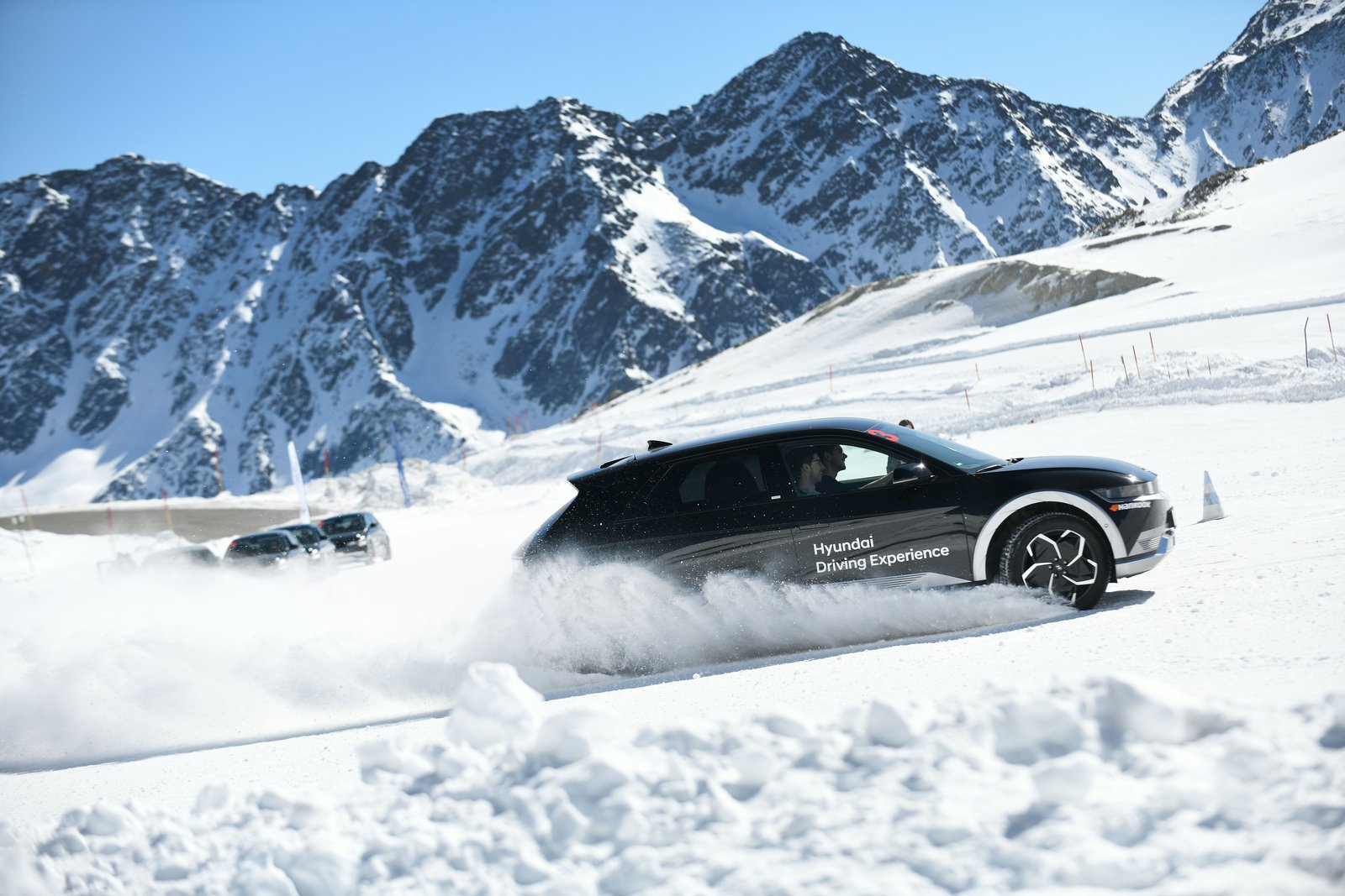 Black Hyundai Ioniq 5 kicking up snow on a frozen driving course