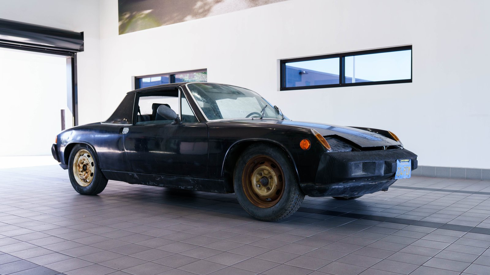 Weathered black 1973 Porsche 914 with rusty steel wheels before restoration