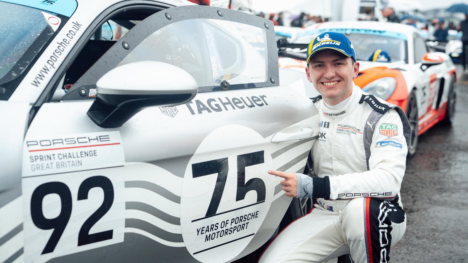 Joshua Rogers pointing at the 75 Years of Porsche Motorsport livery on his No. 92 Cayman