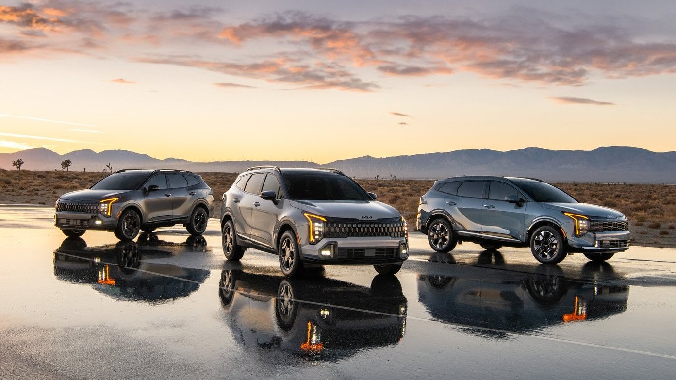 Three 2027 Kia Sportage models parked on wet pavement at sunset