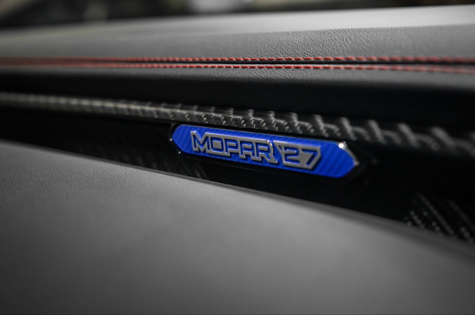 Blue Mopar '27 badge on a carbon-trimmed dashboard
