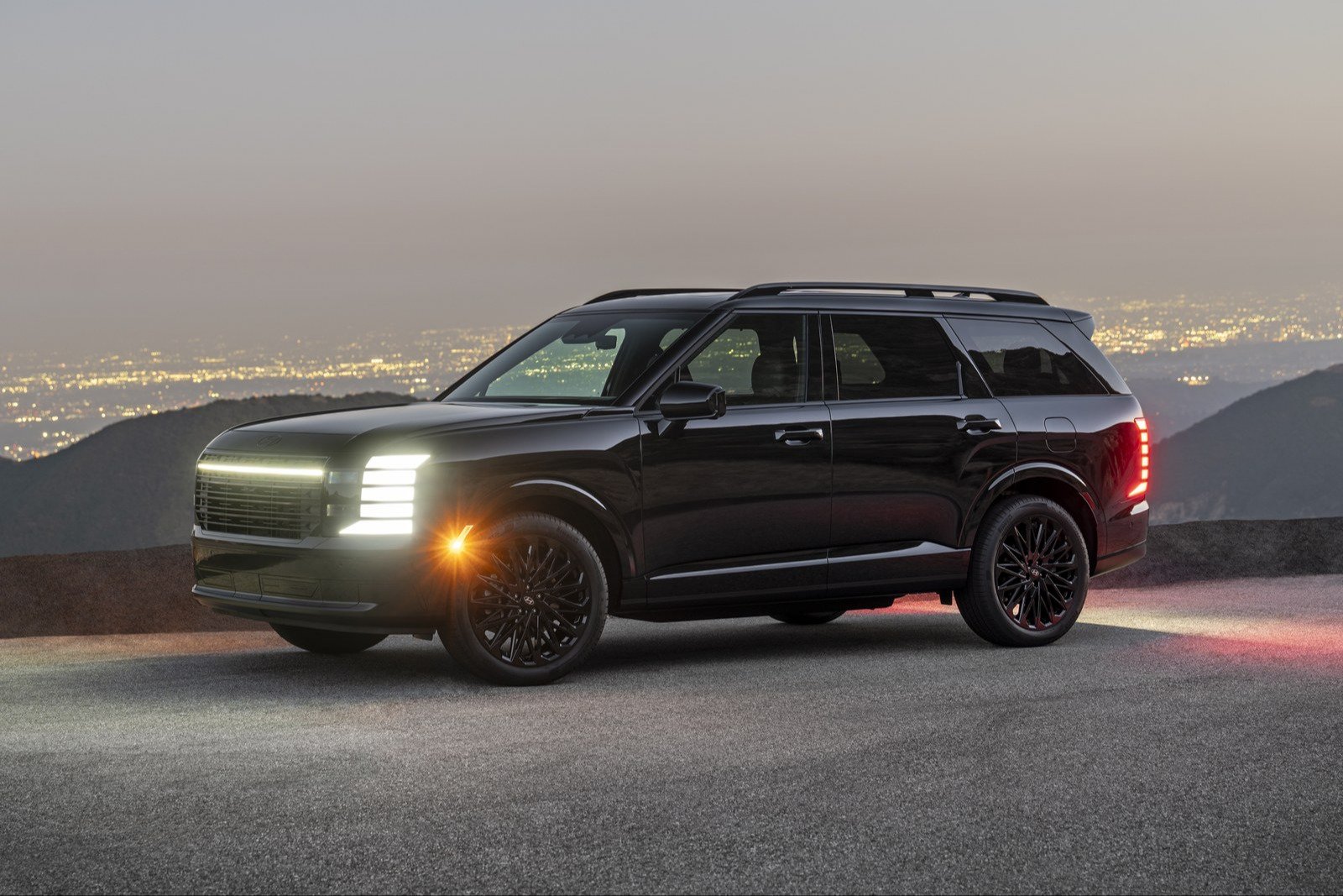Black 2027 Hyundai Palisade Hybrid Calligraphy Black Ink at dusk above a city